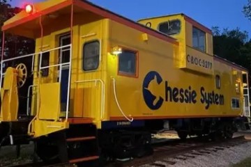 Bright yellow caboose labeled 'Chessie System' on display at dusk.